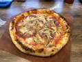 Domowa pizza z pieczarkami i salami na drewnianej desce.
