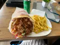 Kebab z frytkami na talerzu, obok puszka napoju.