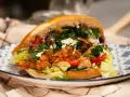 Domowy kebab z kurczakiem, warzywami i sosem na talerzu.