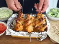 Domowy kebab: grillowane szaszłyki z kurczaka w tacce, obok miseczki z warzywami i tortille.