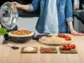 Gotowa pizza w piecyku, składniki na blacie: pomidorki, ser, rukola, szynka.