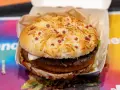 Burger Drwala z podwójnym mięsem, serem i kawałkami bekonu na bułce.