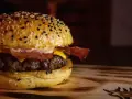 Soczysty domowy burger z bekonem i serem na bułce z sezamem.