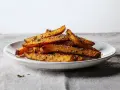 Chrupiące frytki z dyni posypane ziołami i parmezanem na białym talerzu.