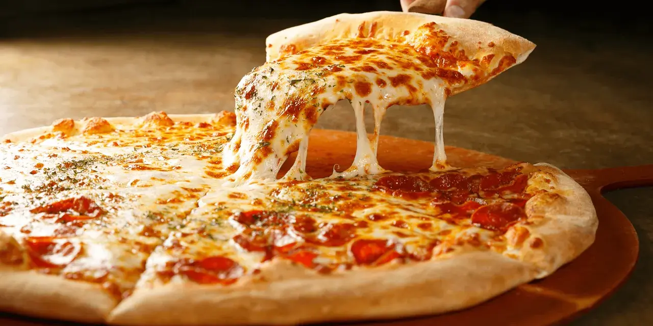 Gorąca pizza z ciągnącym się serem i pepperoni na desce.
