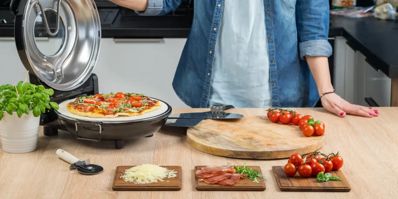 Gotowa pizza w piecyku, składniki na blacie: pomidorki, ser, rukola, szynka.