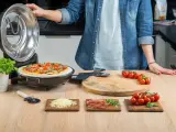 Gotowa pizza w piecyku, składniki na blacie: pomidorki, ser, rukola, szynka.