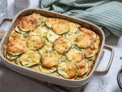 Zapiekanka z cukinii z serem i ziołami w naczyniu żaroodpornym.
