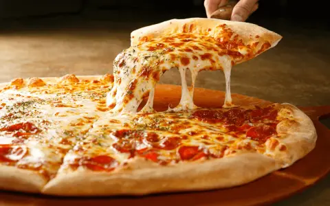 Gorąca pizza z ciągnącym się serem i pepperoni na desce.