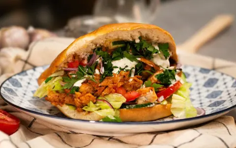 Domowy kebab z kurczakiem, warzywami i sosem na talerzu.