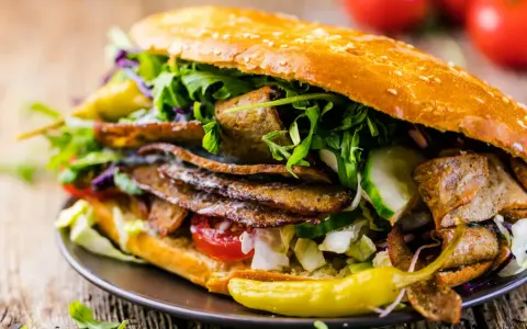 Duży kebab w bułce z mięsem, warzywami i pikantną papryczką.