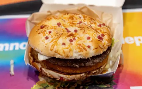 Burger Drwala z podwójnym mięsem, serem i kawałkami bekonu na bułce.