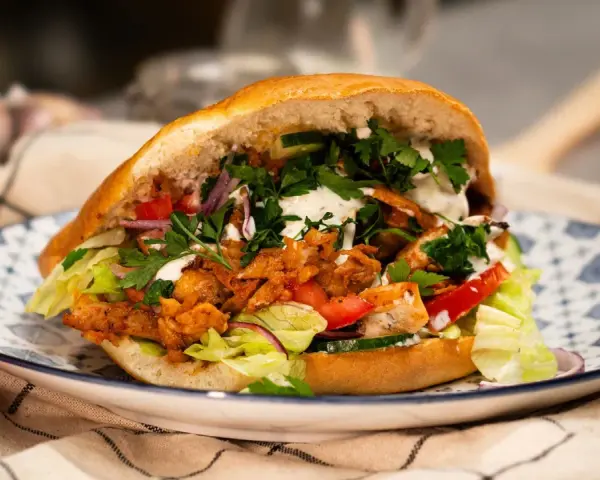 Domowy kebab z kurczakiem, warzywami i sosem na talerzu.