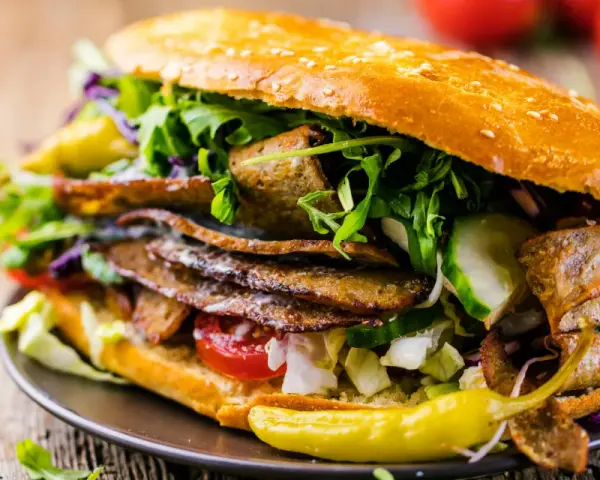 Duży kebab w bułce z mięsem, warzywami i pikantną papryczką.