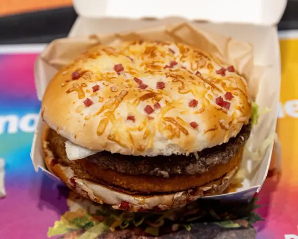 Burger Drwala z podwójnym mięsem, serem i kawałkami bekonu na bułce.