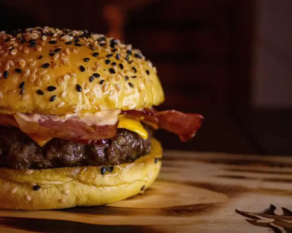 Soczysty domowy burger z bekonem i serem na bułce z sezamem.