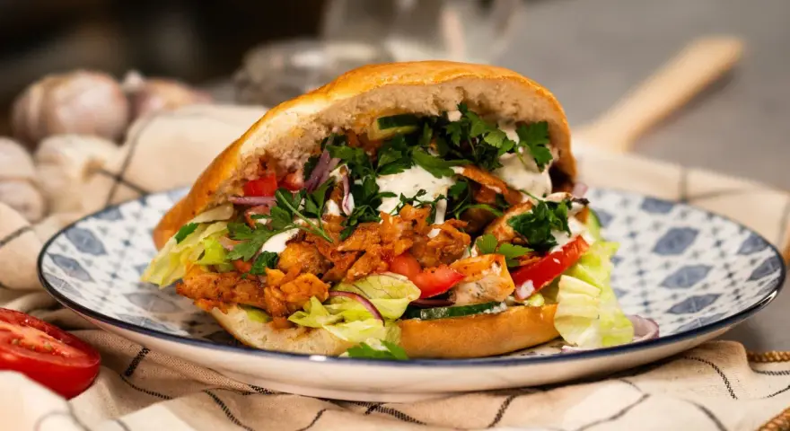 Domowy kebab z kurczakiem, warzywami i sosem na talerzu.