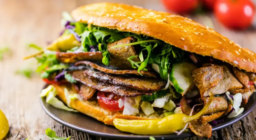 Duży kebab w bułce z mięsem, warzywami i pikantną papryczką.