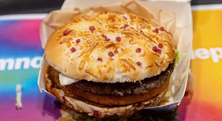 Burger Drwala z podwójnym mięsem, serem i kawałkami bekonu na bułce.